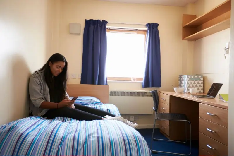 Student Uses Mobile Phone in Bedroom of budget Accommodation 