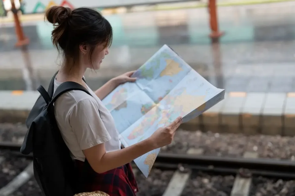 A young woman traveler standing with map choose where to travel